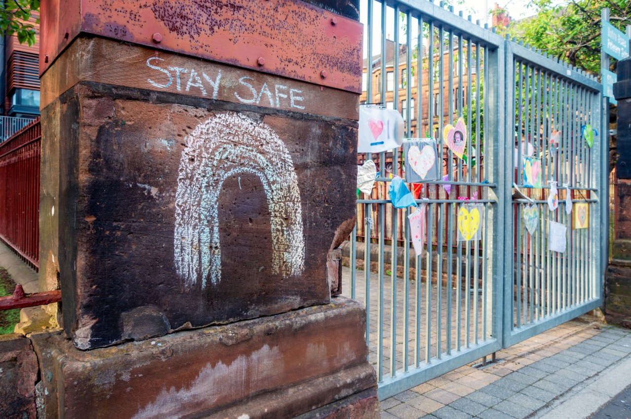 School gates with the words 'stay safe' written in chalk.